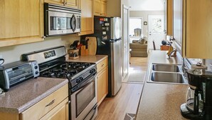 Une cuisine dotée de meubles en bois, d’un réfrigérateur en acier inoxydable, d’un four à micro-ondes, d’une cuisinière et d’une machine à café.