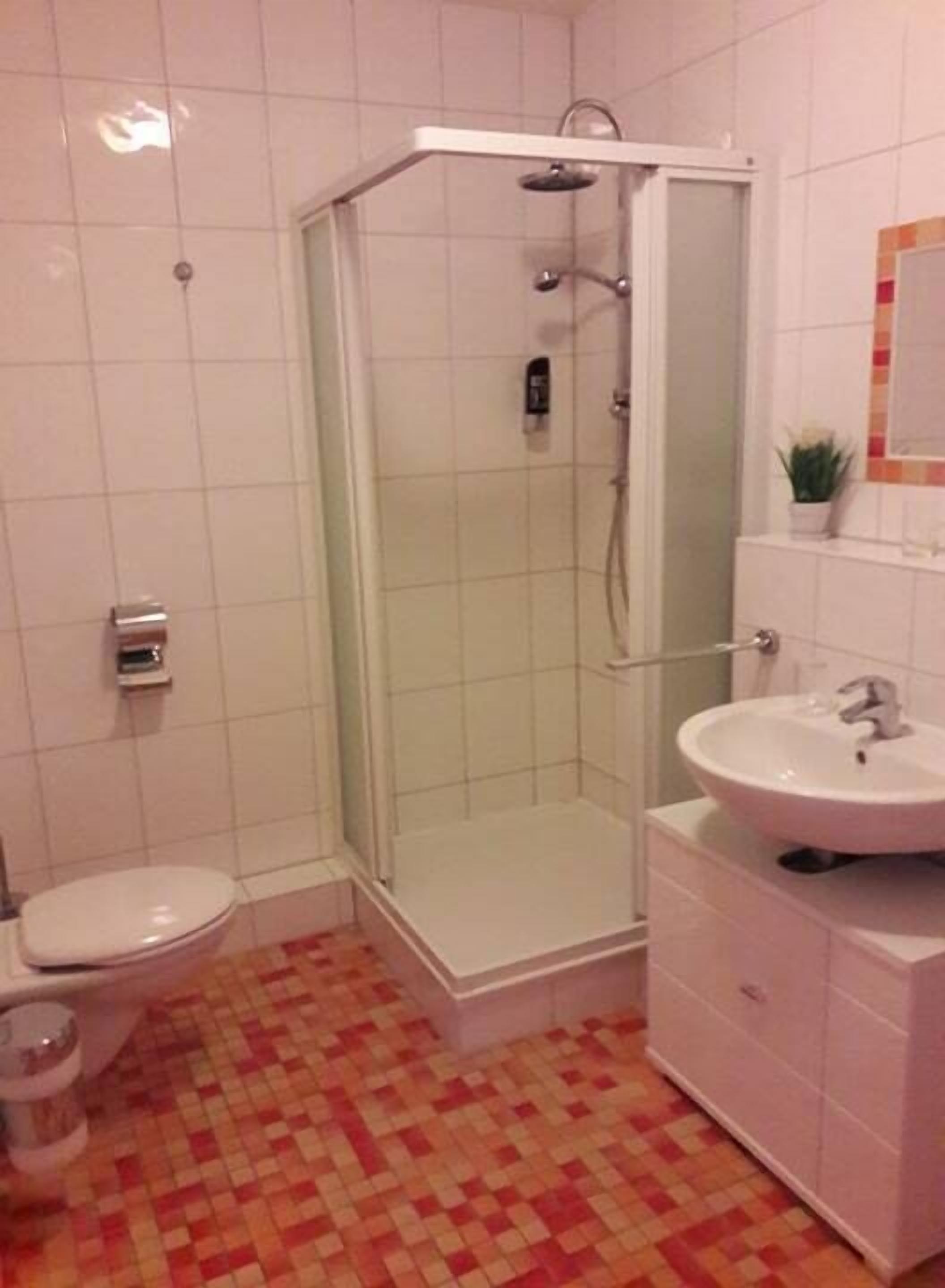 A bathroom with a shower, toilet, and sink.