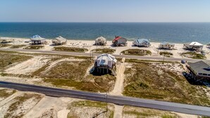 Vista aérea de una zona costera con varias casas de playa, una carretera y el océano al fondo.