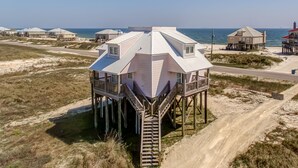 Una casa de playa con un techo octogonal único, elevada sobre pilotes, con una escalera que conduce a una terraza.