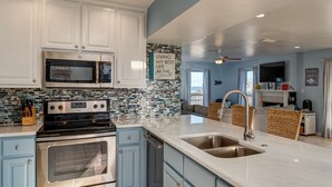 Una cocina moderna con armarios blancos, una estufa de acero inoxidable y un salpicadero de azulejos.