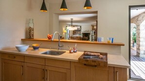 A kitchen with a sink, a wooden countertop, a mirror, and hanging pendant lights. -  Big pool (19m), large beds, AIRCON, fast WIFI, EV charger, BBQ, peace and quiet (Cagnes-Sur-Mer)