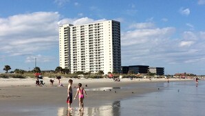 Un hotel frente al mar con un edificio alto en el fondo.