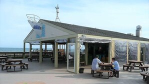 Un restaurante frente al mar con terraza y vista al océano.