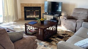 Una sala de estar con chimenea, televisor y dos sofás.