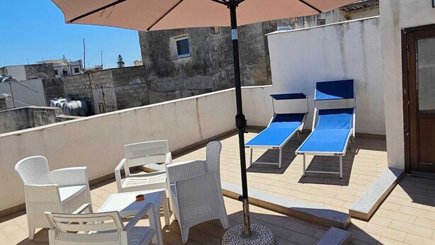 Een dakterras met lounge stoelen, een tafel en een parasol.