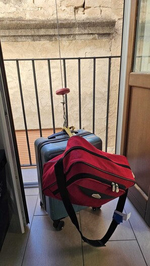 A balcony with a luggage trolley, a red bag, and a suitcase.