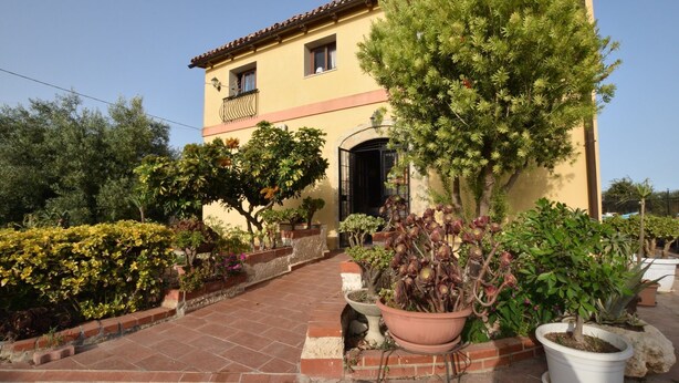 A yellow building with a tiled roof, a balcony, and a paved entrance. - Country Cottage / Gite - Siracusa (Siracusa)