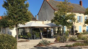 Ein Innenhof mit einem Café, Sitzgelegenheiten im Freien und einem Gebäude mit einer steinernen Fassade.