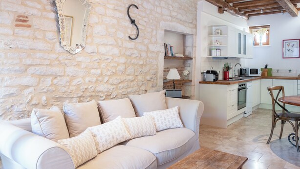 Ein gemütliches Wohnzimmer mit einem beigen Sofa, einem Holztisch und einer Steinwand.