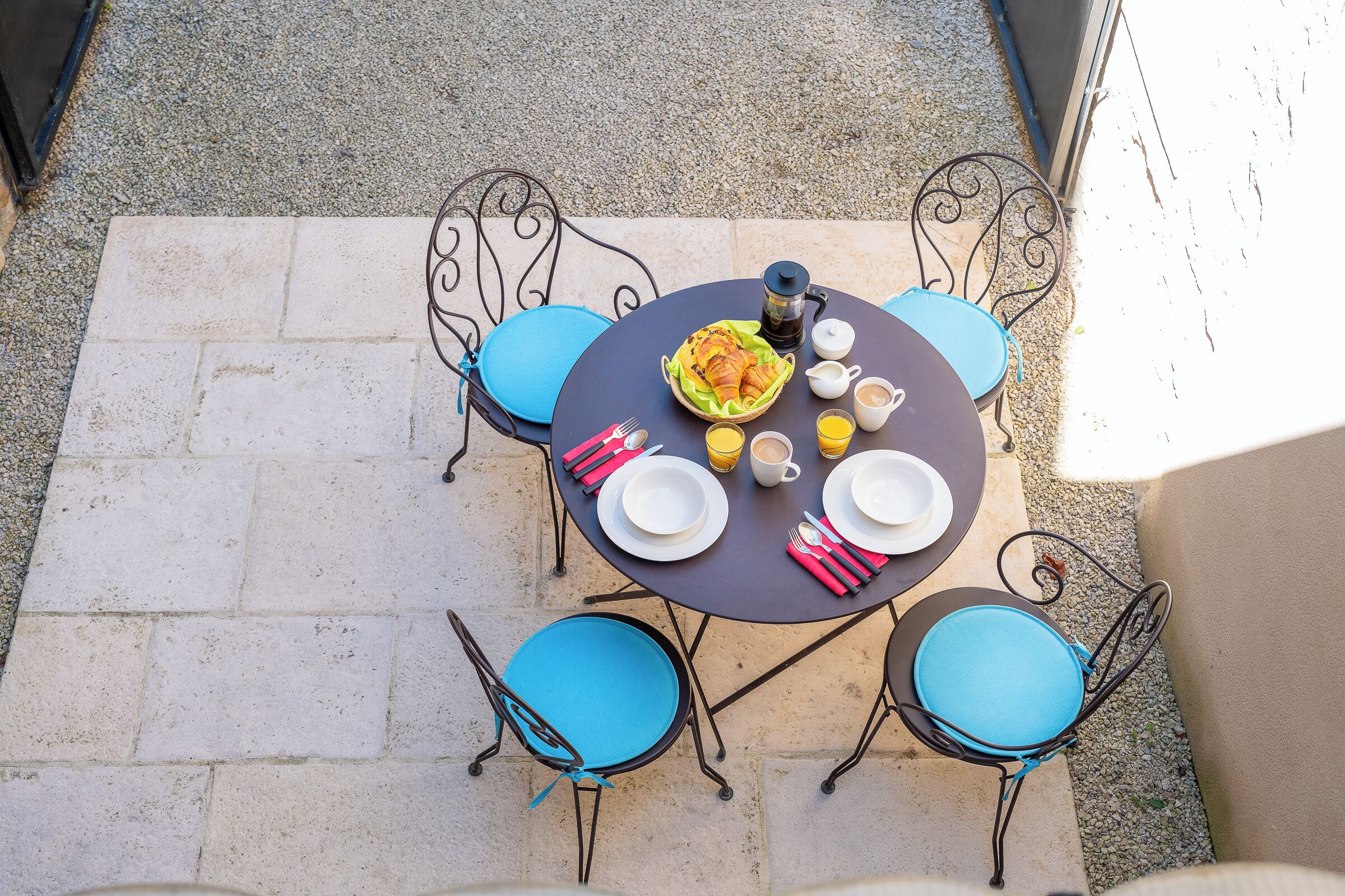 A round table with chairs, plates, cups, and a bottle of water.
