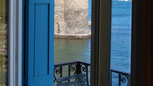 A view of a stone tower with a dome through a blue door, overlooking a body of water.