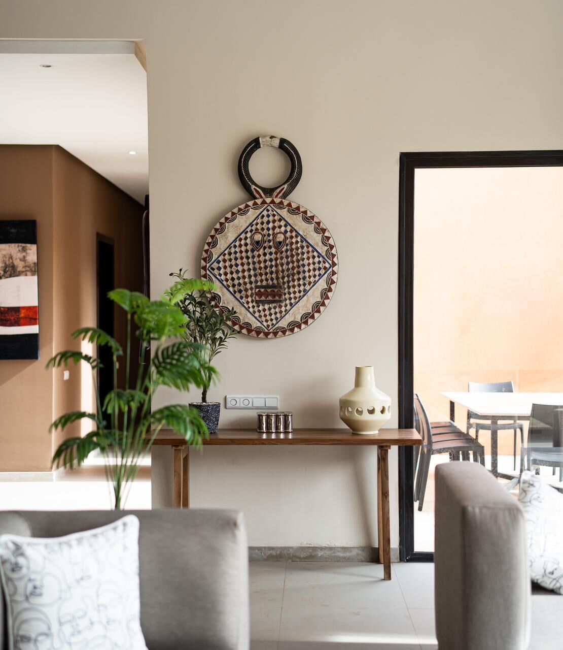 A modern living room with a sofa, a coffee table, a decorative wall hanging, and a potted plant.