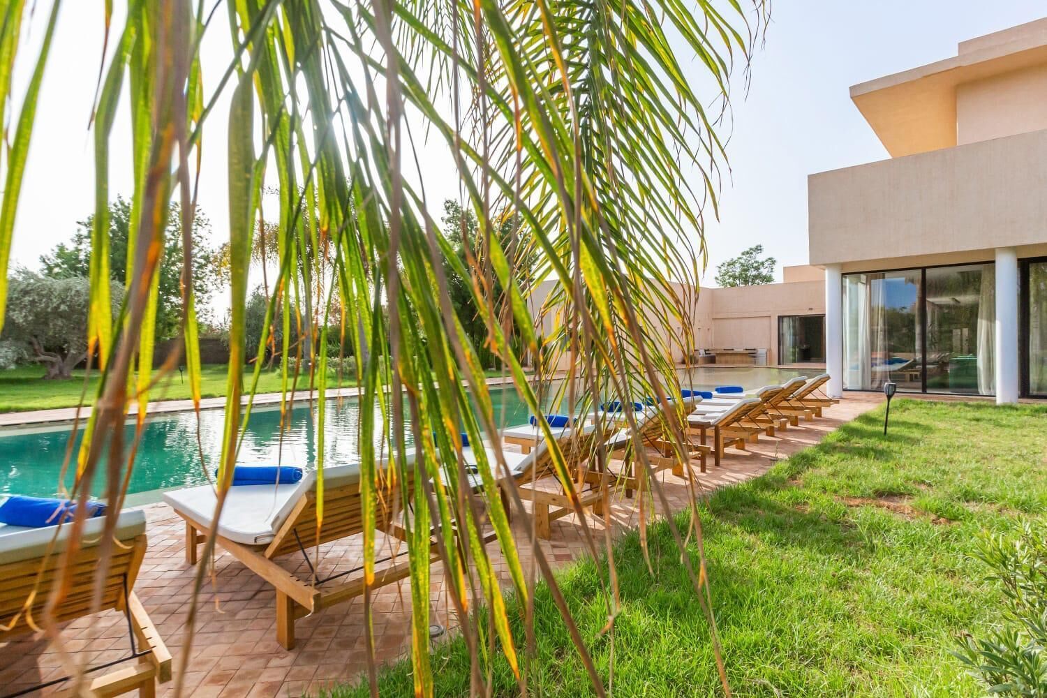 Un espace aménagé au bord de la piscine, avec des chaises longues, et un bâtiment moderne en arrière-plan.