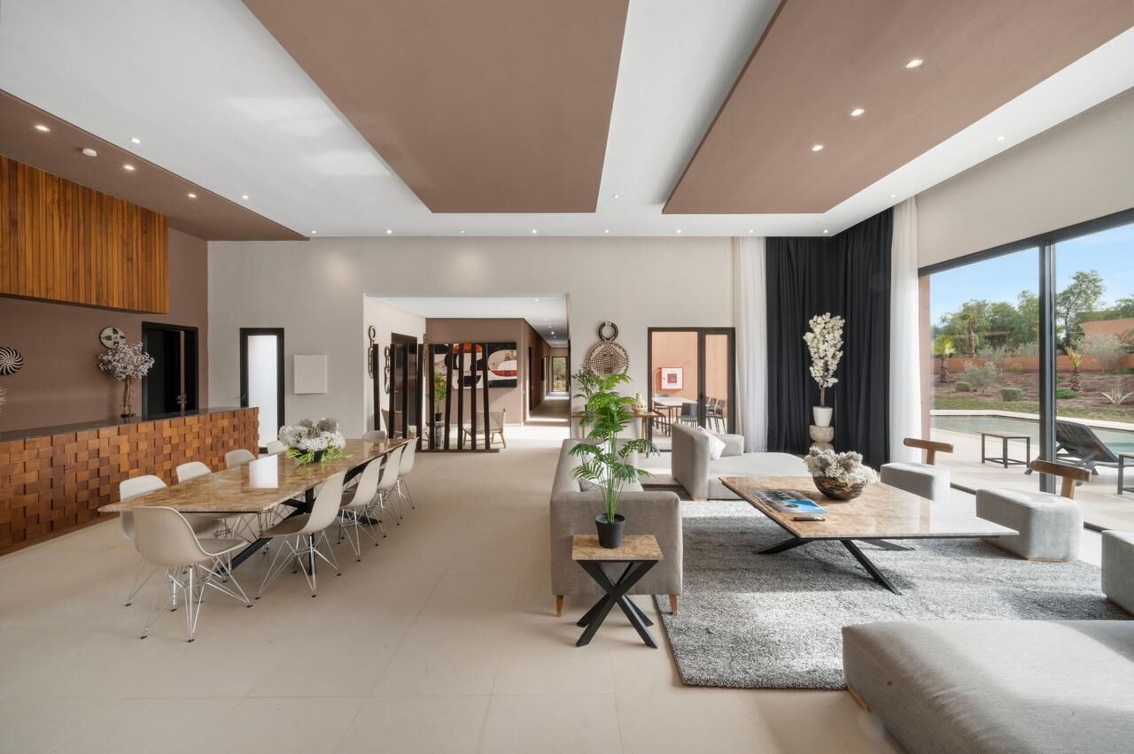 Amplia sala de estar con una mesa de comedor, sofás y un ventanal con vistas al exterior.
