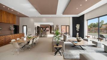 Amplia sala de estar con una mesa de comedor, sofás y un ventanal con vistas al exterior.