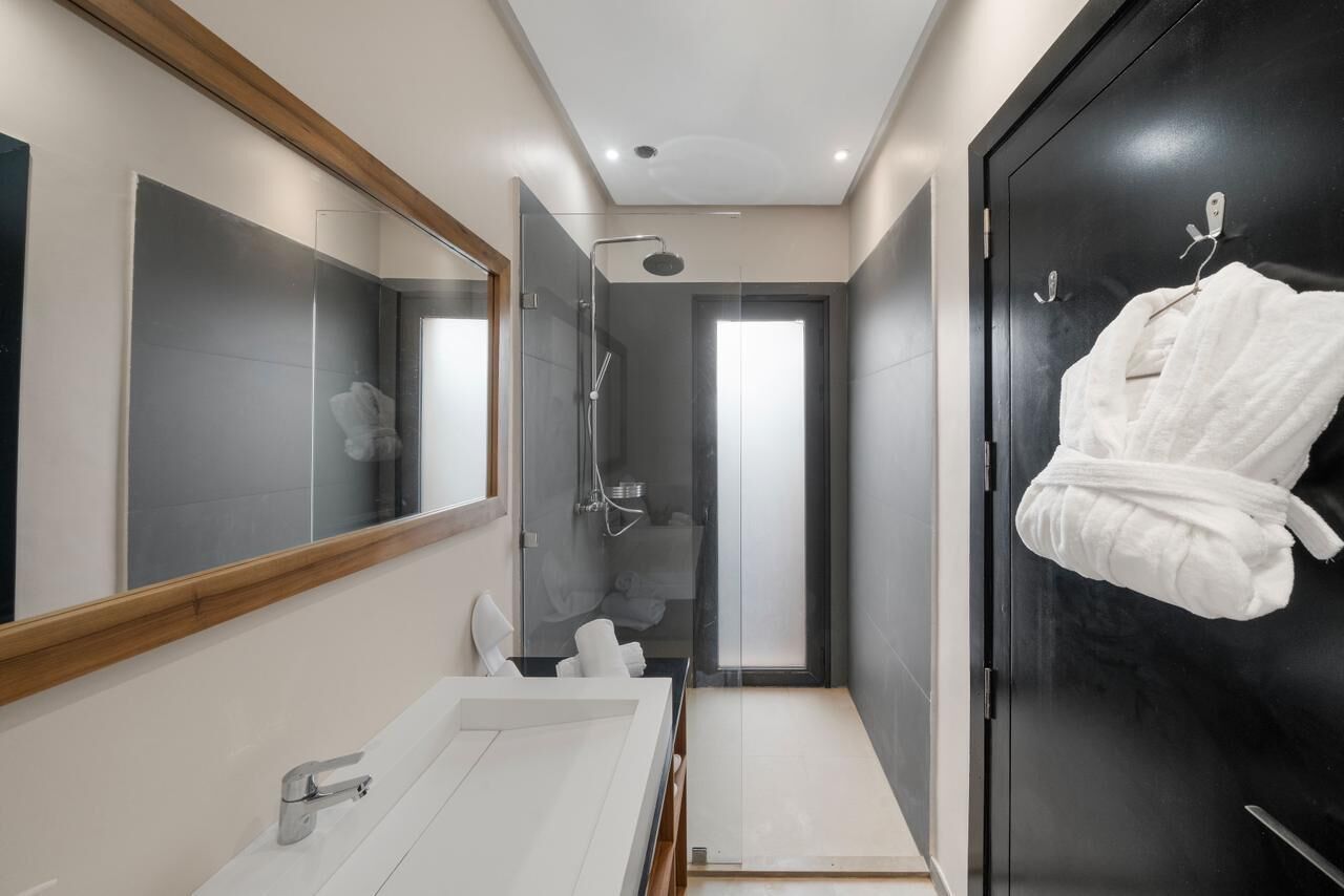 Une salle de bain moderne avec un grand miroir, une douche et une robe accrochée à la porte.