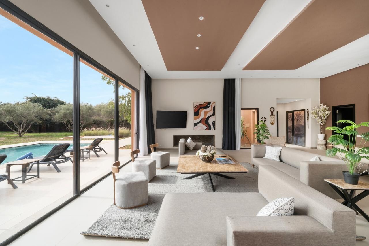 Un salon moderne doté d’une grande fenêtre, d’une cheminée et offrant une vue sur la piscine.