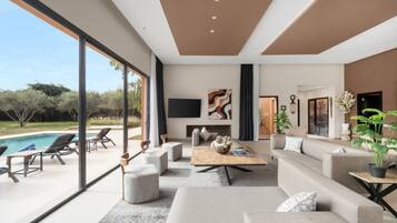 Un salon moderne doté d’une grande fenêtre, d’une cheminée et offrant une vue sur la piscine.