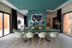 Un comedor moderno con una mesa de vidrio, sillas verdes y una pared de acento color aguamarina.