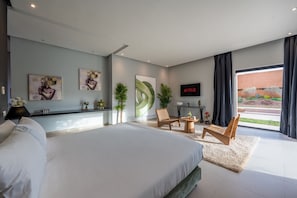 A modern bedroom with a large bed, a TV, and a view of the outdoors. - Villa 865 + (Marrakech)