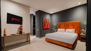 A modern bedroom with a large bed, a TV mounted on the wall, and a desk with a vase of flowers. - Villa 865 + (Marrakech)