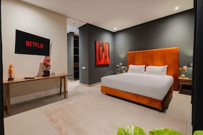 A modern bedroom with a large bed, a TV mounted on the wall, and a desk with a vase of flowers. - Villa 865 + (Marrakech)