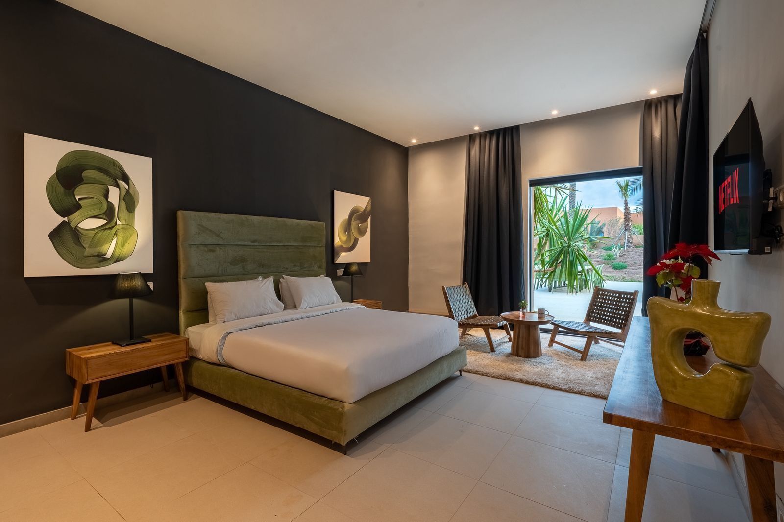 Ein modernes Schlafzimmer mit einem großen Bett, Nachttischen, einem Schreibtisch, Stühlen und Kunstwerken an den Wänden.