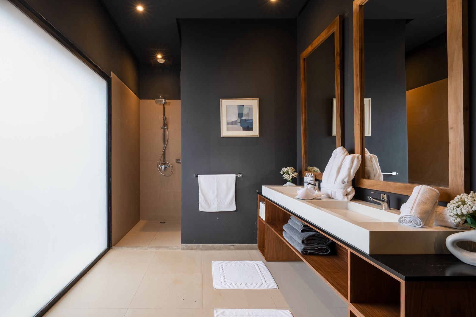 Un baño moderno con ducha, un espejo grande y tocador con toallas.