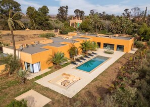 Una casa moderna con piscina, mobiliario exterior y vistas del paisaje circundante.