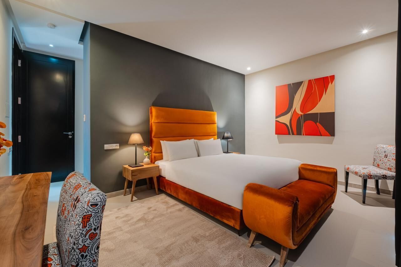 Una camera d'albergo moderna con un grande letto, un comodino, una scrivania e una sedia.