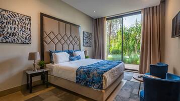 Hotelkamer met een groot bed, een bureau, twee stoelen en uitzicht op groen.