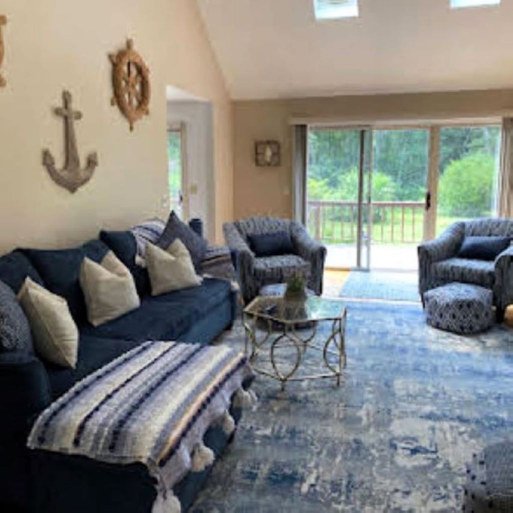 Un salon avec un canapé bleu, des fauteuils à motifs et une table basse.