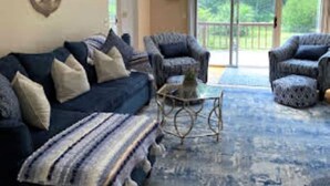 Un salon avec un canapé bleu, des fauteuils à motifs et une table basse.