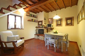 Uma sala de estar aconchegante com lareira, uma mesa de jantar com cadeiras, um sofá e uma escada.