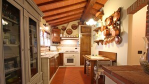Une cuisine avec des meubles de rangement en bois, un carrelage au sol et un porte-ustensiles suspendu au plafond.