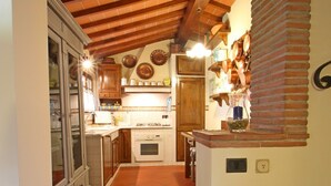 Une cuisine étroite avec un sol carrelé, des meubles en bois et une arche en briques.