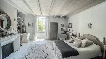 Une chambre à coucher avec un lit, une chaise, un bureau, une cheminée et une fenêtre.