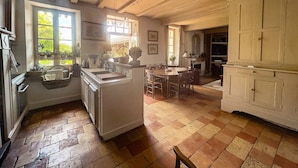 Une cuisine spacieuse dotée d’un grand îlot central, de meubles en bois et d’un coin repas agrémenté d’une cheminée.