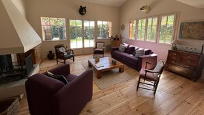 Ein geräumiges Wohnzimmer mit Kamin, Holzboden und großen Fenstern.