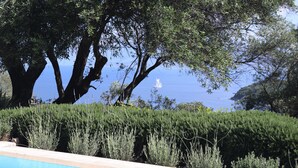 Un espace piscine offrant une vue sur la mer et sur un voilier au loin.