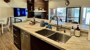 A modern kitchen with a large island, stainless steel sink, and wooden accents. - Lakefront Townhome | Prvt Beach & Decks | Sleeps 6 (Zephyr Cove)