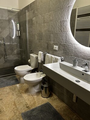 Een bad/douchecombinatie, een haardroger, een bidet, handdoeken