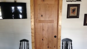 Una puerta de madera con un ventanal pequeño, flanqueada por dos sillas negras.