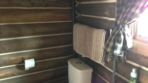 Interior de una cabaña de madera con literas, una ventana con cortinas, un inodoro y una pared decorada con estrellas.