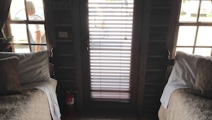 Una habitación con dos camas, una ventana con persianas, un extintor y una puerta.