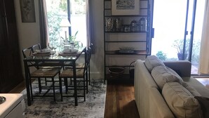 Un coin repas avec une table dressée pour quatre personnes, un canapé et un espace cuisine équipé d’un réfrigérateur.