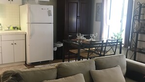 Un salon avec un canapé beige, une table à manger avec des chaises, un buffet en bois foncé et un réfrigérateur blanc.