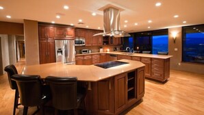 Une cuisine spacieuse avec des meubles en bois, un grand îlot central et une vue sur l’extérieur.