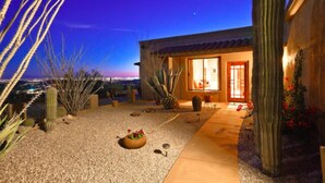 Une maison de style désertique avec une allée en gravier, des cactus et un petit jardin.